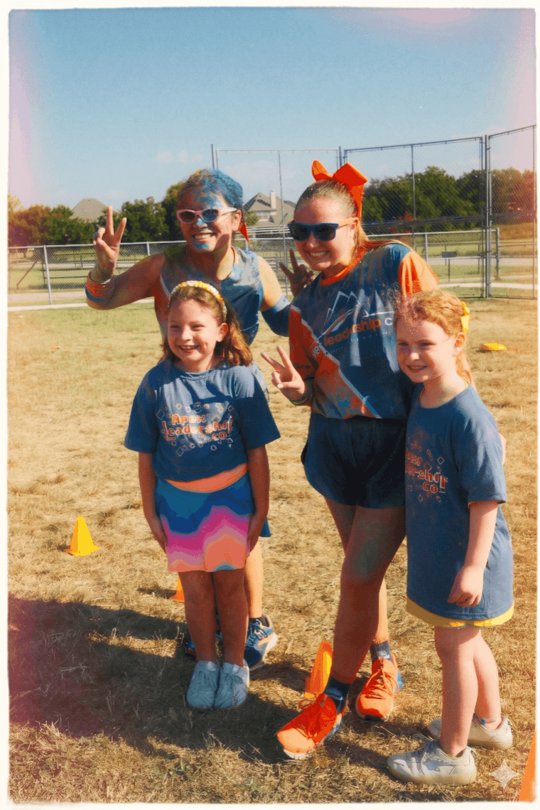 Apex coaches posing with young students on a school field during a fun run