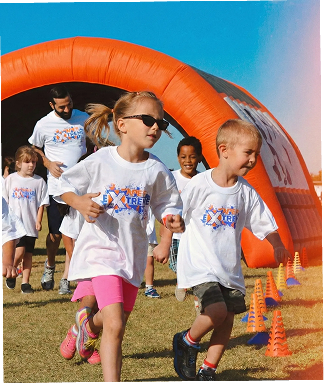 Smiling students running out of an inflatable arch at an Apex fun run