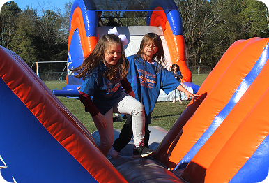 Students climbing an inflatable slide at an Apex Obstacle Course
