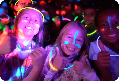 Smiling students with glow sticks at an Apex Remix dance party