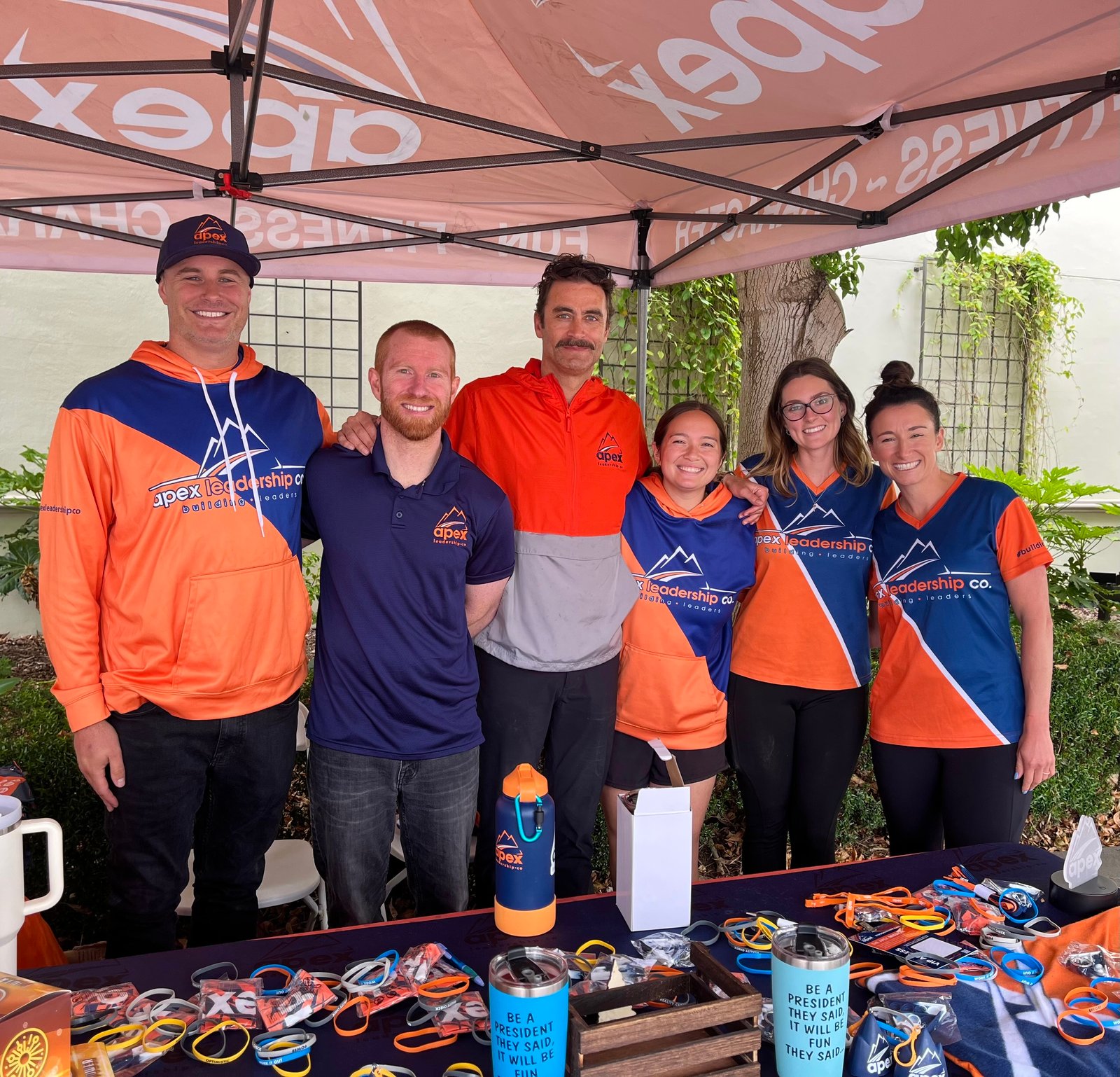 The Apex San Diego team at an event tent with Apex wristbands and giveaways
