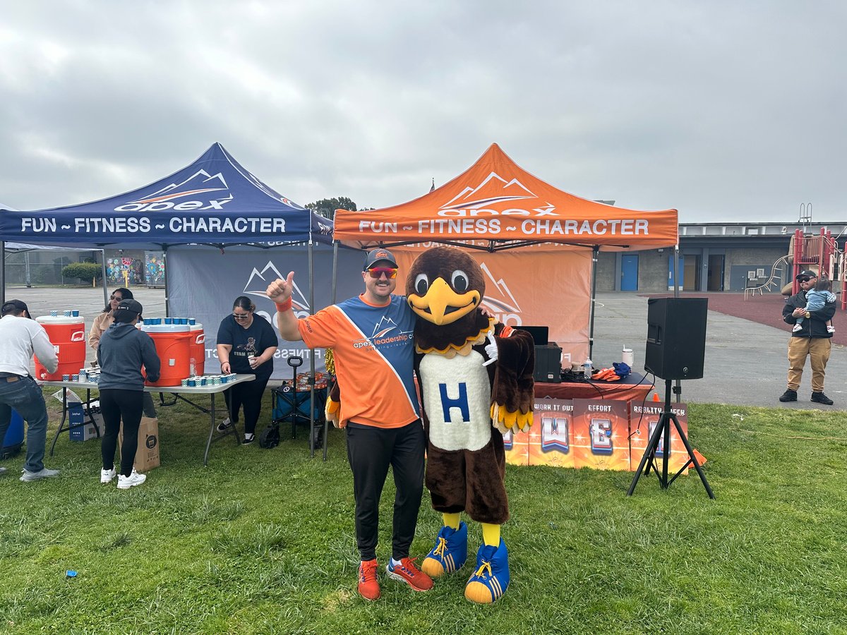 An Apex San Diego coach giving a thumbs up with a school mascot