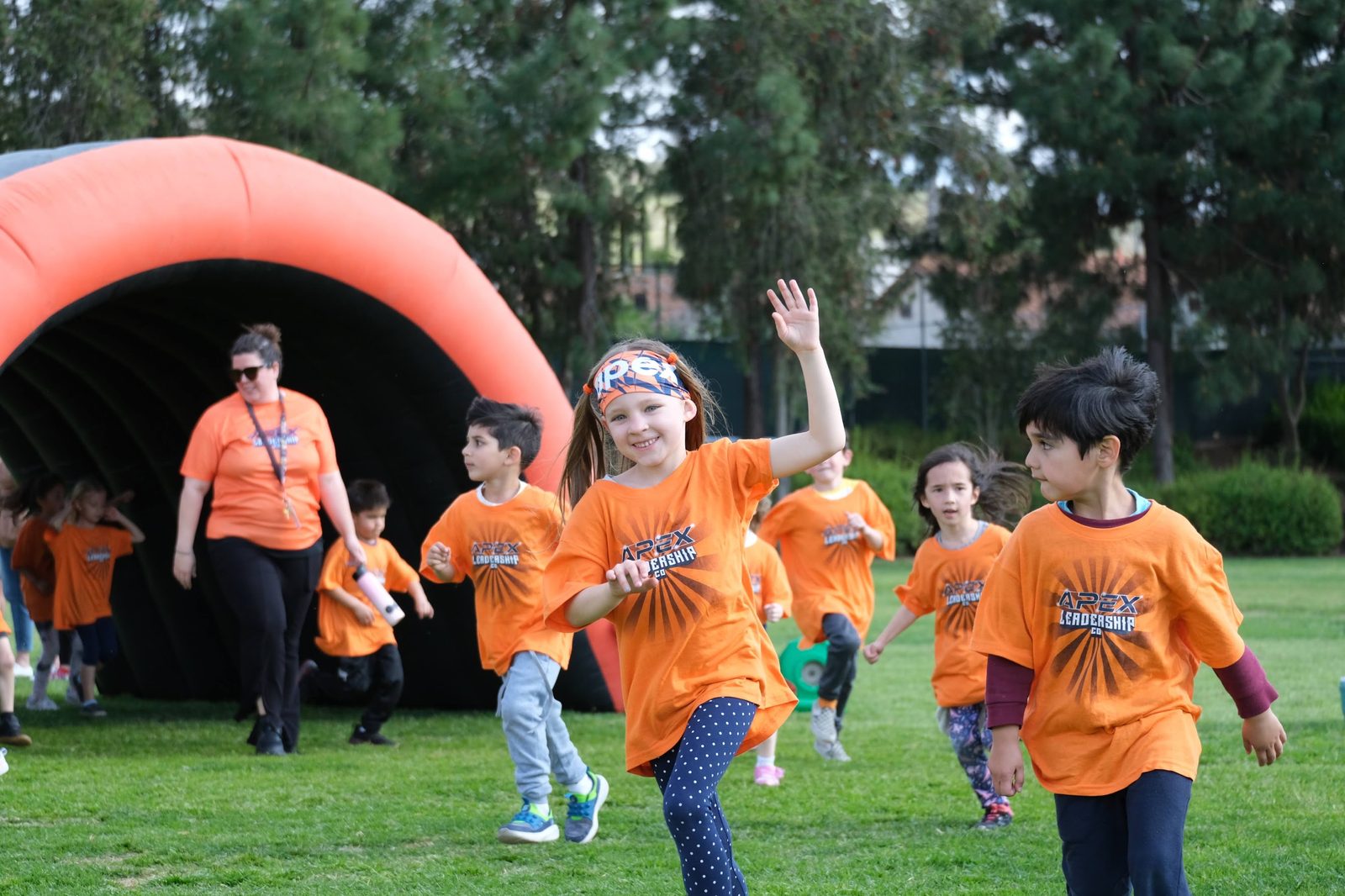 Students in orange Apex shirts running out of the Fun Run arch on event day