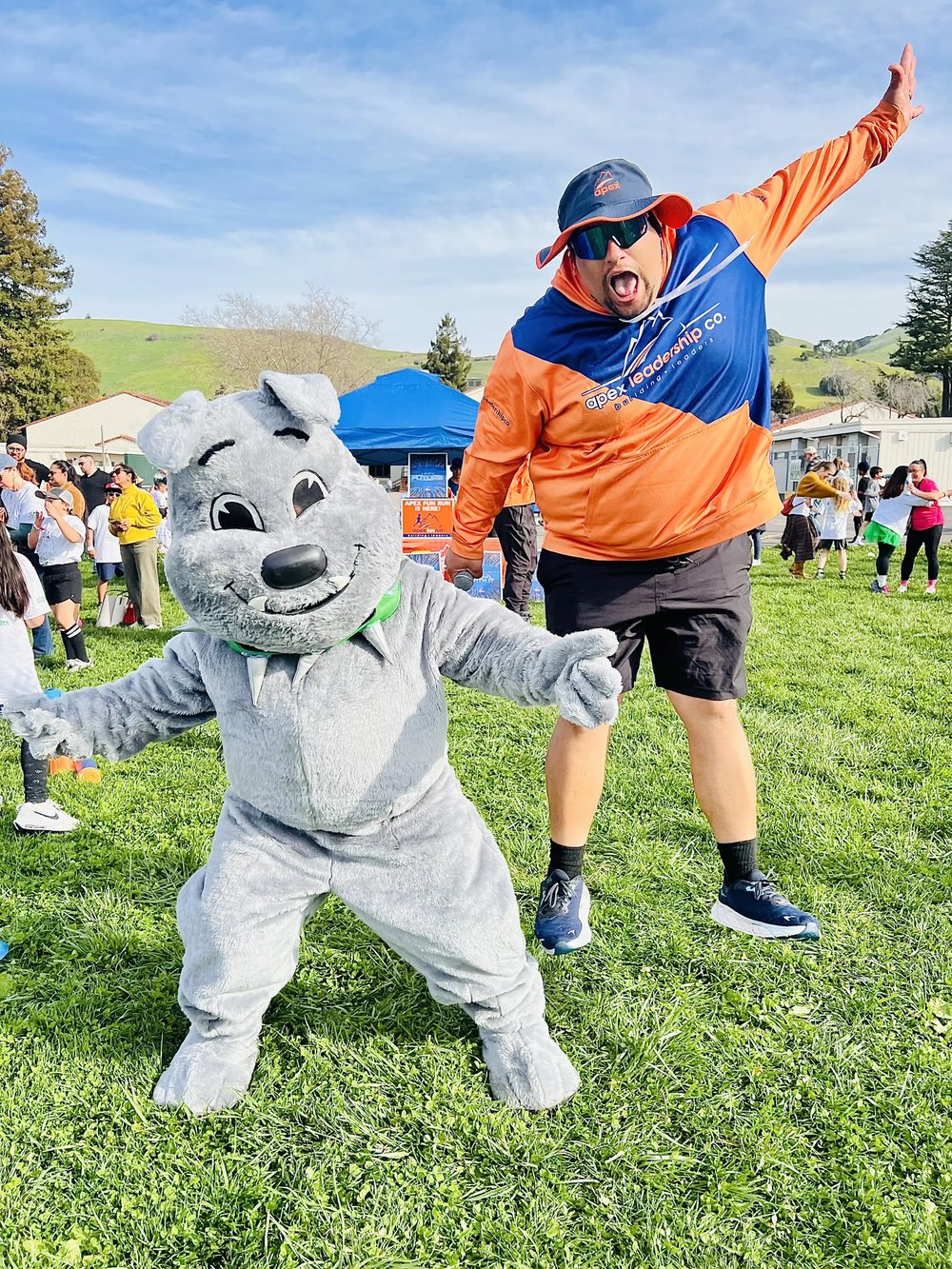 An Apex coach dancing with a school mascot at a fun run