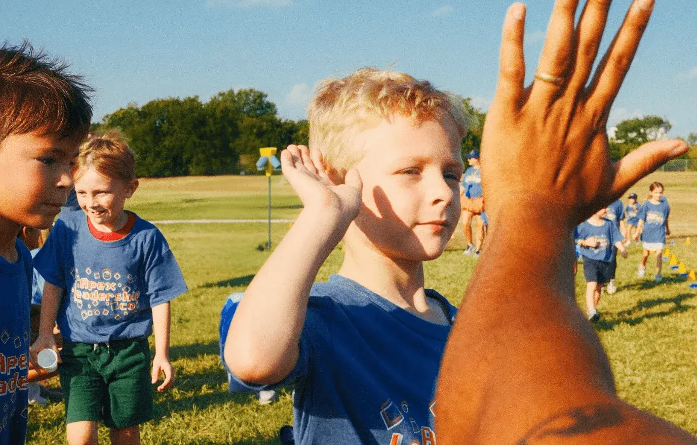 Young students giving high fives to an Apex coach at a school fun run